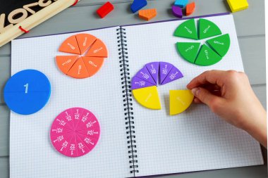 Çocuklar gri ahşap arka planda veya masada renkli matematik kesirlerini oynatıyorlar. Çocuklar için ilginç, yaratıcı, komik bir matematik. Eğitim, okul konseptine geri dönelim. Geometri ve matematik materyalleri.
