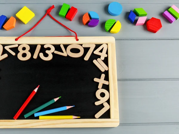 Close up of blackboard with numbers and Multicolored math fractions on the on gray wooden table. Interesting math for kids background. Education, back to school concept