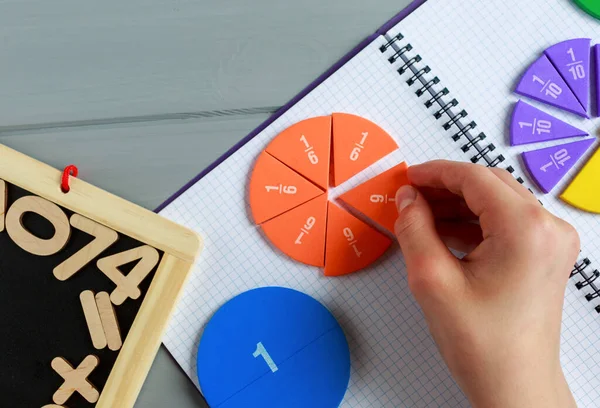 Çocuklar gri ahşap arka planda veya masada renkli matematik kesirlerini oynatıyorlar. Çocuklar için ilginç, yaratıcı, komik bir matematik. Eğitim, okul konseptine geri dönelim. Geometri ve matematik materyalleri.