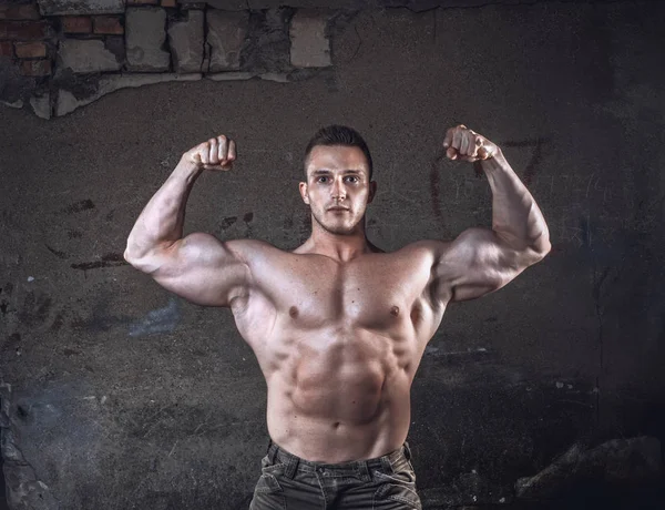 Bodybuilder on grunge wall — Stock Photo, Image