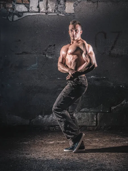 Bodybuilder poseren over grunge muur — Stockfoto