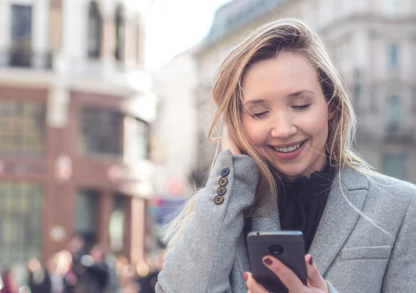 Donna in piedi per strada e utilizzando il telefono cellulare — Foto Stock