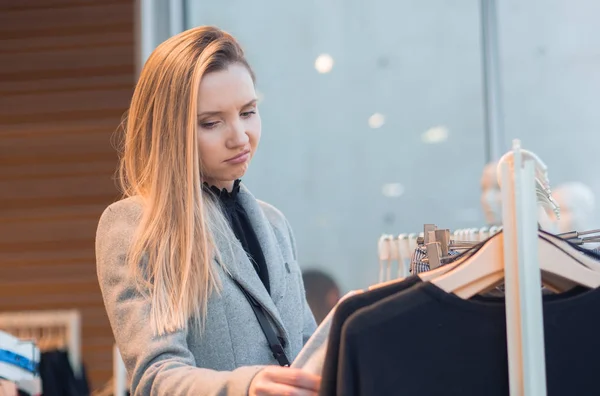 Irritado feminino escolher roupas na loja de varejo — Fotografia de Stock