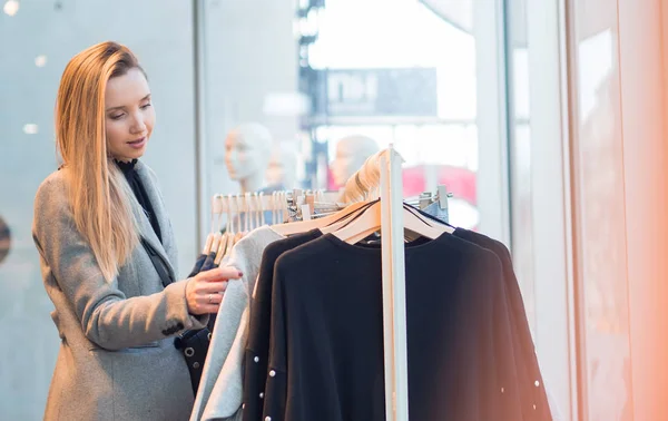 Jovem na moda escolhendo roupas na boutique — Fotografia de Stock