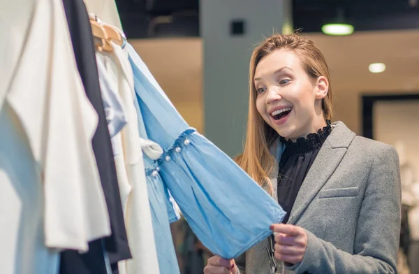 Förvånad brunett flicka i trendiga boutique att välja kläder — Stockfoto