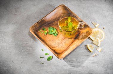 Dilimlenmiş limonlu cam bardakta taze bitki çayı.