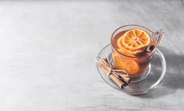 Cup of fruit tea with dry orange and cinnamon on gray background — Stock Photo, Image