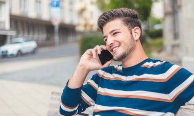 Akıllı telefonuyla konuşan neşeli bir gencin yakın portresi..