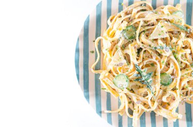 Beyaz arka planda izole edilmiş ekşi kremalı ve otlu makarna tabağını kapat. Üst Manzara. Lezzetli tagliatelle - spagetti