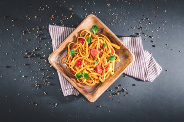 Koyu masa üzerinde domates soslu bir tabak makarna. Lezzetli bir porsiyon tagliatelle. Siyah üzerine izole edilmiş.