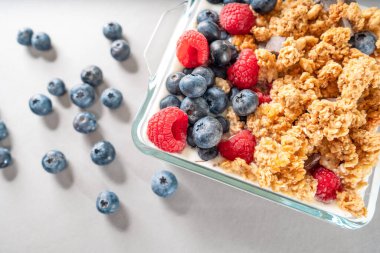 Süt ve böğürtlenli granola. Sağlıklı yemek. Ahududu ve yaban mersinli mısır gevrekleri, gri renkte izole edilmiş.