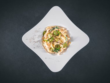 Ekşi kremalı ve otlu makarna tabağı, siyah arka planda izole. Üst Manzara. Tagliatelle, spagetti.