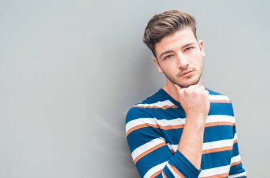 Gri arka planda, dışarıda izole edilmiş sıradan bir genç adam.