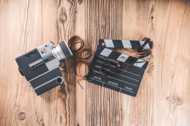 Alkış tahtası ve film şeridi olan eski bir kamera. Telif alanı olan ahşap bir masa. Retro sinema kavramı