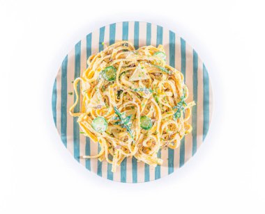 Beyaz arka planda ekşi kremalı ve otlu makarna tabağı. Üst Manzara. Lezzetli tagliatelle - spagetti