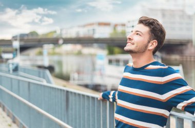 Neşeli, güzel genç bir adamın yan görüntüsü. Neşeli, güzel bir adam güzel bir günde dinleniyor. Kaygısız adam.