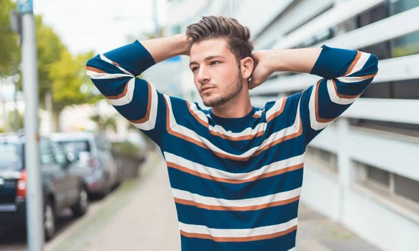 Young beautiful man posing in the street. Guy with modern hairstyle, outdoor