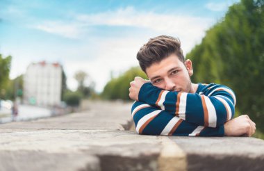 Kameraya bakan yalnız bir genç adam. Bekar, güzel bir adam, açık havada.