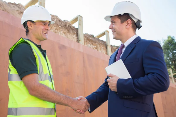 Empresario agitando las manos con constructor en el sitio de construcción —  Fotos de Stock
