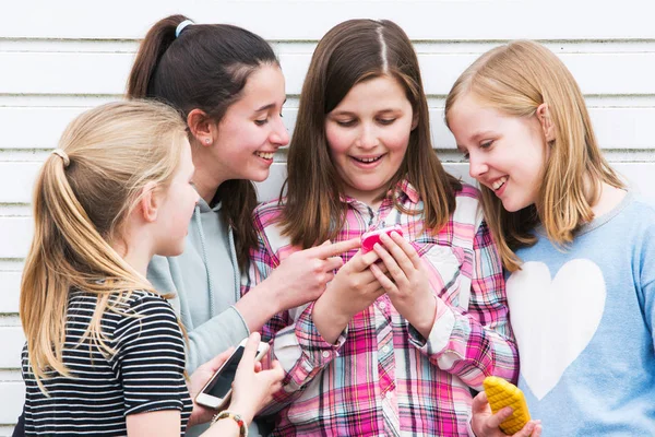 屋外の携帯電話でメッセージを見ている若い女の子のグループ — ストック写真