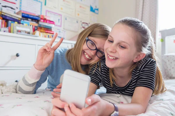 Twee jonge meisjes poseren voor Selfie In slaapkamer — Stockfoto