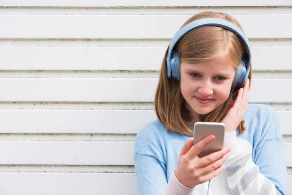 Pre adolescente chica usando auriculares y escuchar música en urbano — Foto de Stock