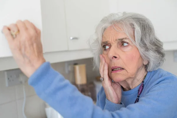 Zapominalskich starszy kobieta z demencją, patrząc w szafie — Zdjęcie stockowe