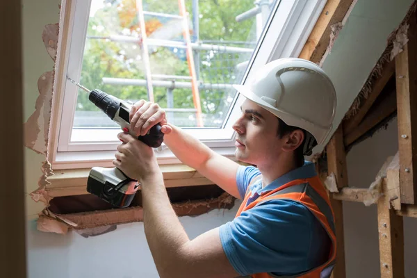 Trabalhador da construção usando broca para instalar a janela de substituição — Fotografia de Stock