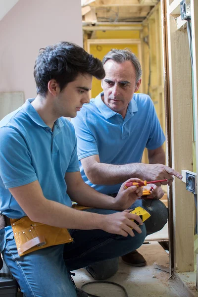 Electricista con aprendiz trabajando en un nuevo hogar — Foto de Stock