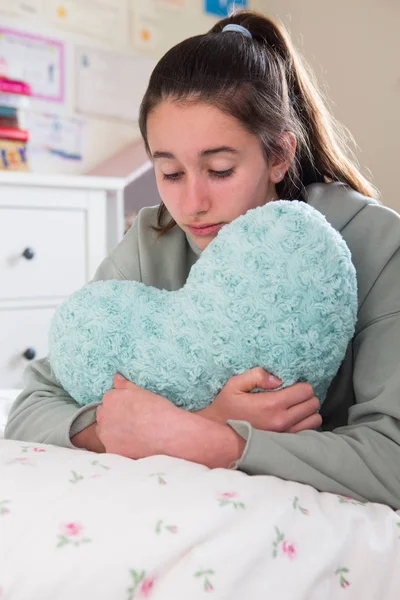 Νέο κορίτσι ξαπλωμένο στο κρεβάτι αγκαλιάζει καρδιά σχήμα μαξιλάρι — Φωτογραφία Αρχείου