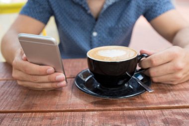 Adamın üstünde hareket eden telefon açık Cafe manifatura, yakın çekim