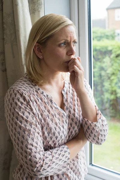 Грустная женщина страдает от агорафобии, выглядывая из окна — стоковое фото