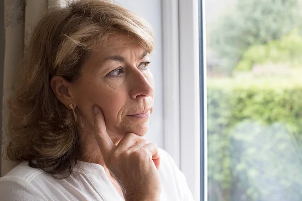 Сумна жінка страждає від агорафобії дивлячись з вікна — стокове фото
