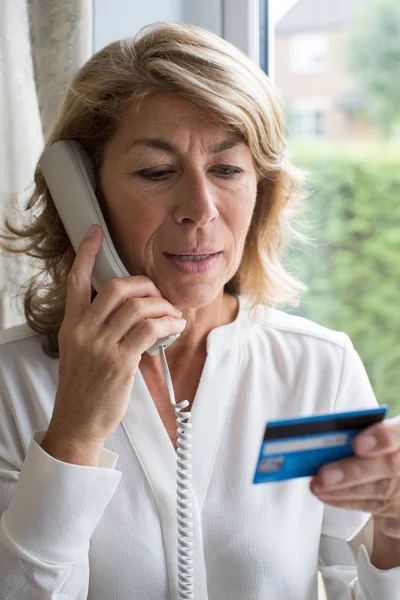 Reife Frau gibt am Telefon Kreditkartendaten an — Stockfoto