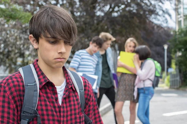 Несчастный мальчик, о котором сплетничают школьные друзья — стоковое фото