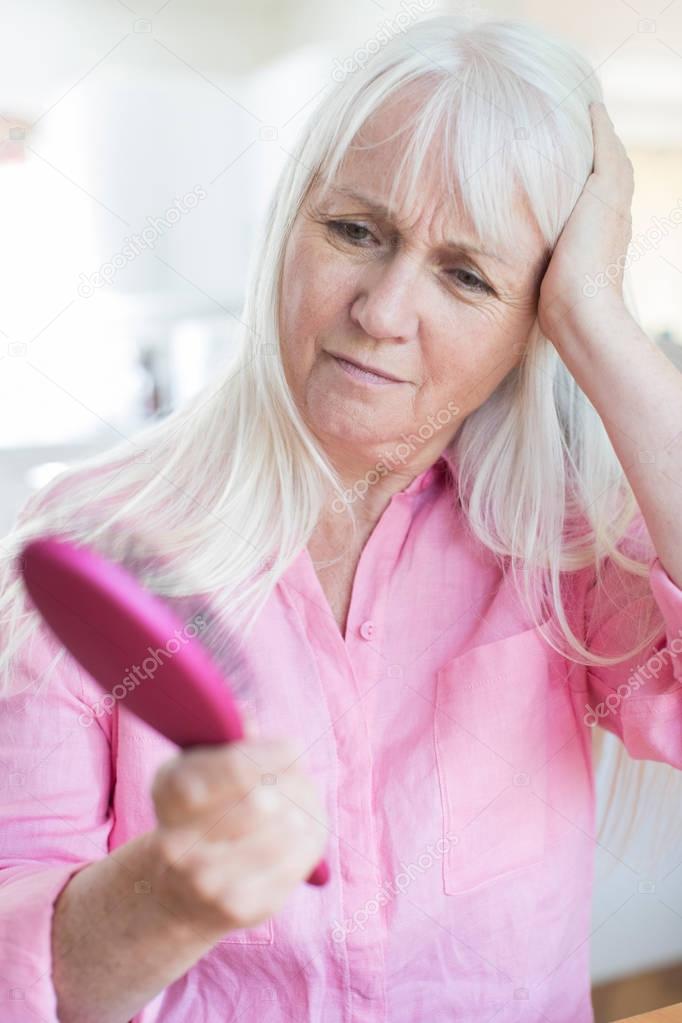 Senior Woman With Brush Concerned About Hair Loss