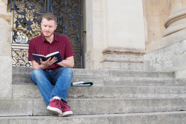 Basamaklarında oturan ve dış Bui okuma Bay Üniversite öğrenci