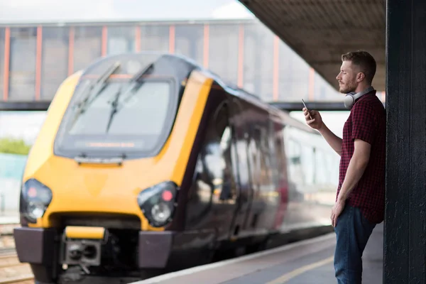 Cep telefonuyla platformda tren istasyonundaki adama — Stok fotoğraf