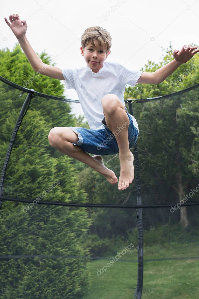 Mid Air Shot Of Boy On Trampoline In Garden