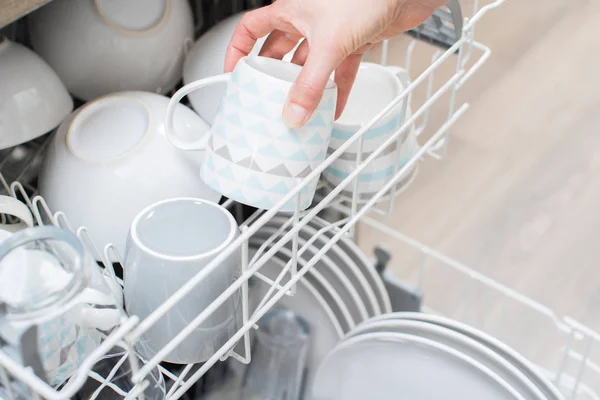 Nahaufnahme einer Frau, die Geschirr in die Spülmaschine lädt — Stockfoto