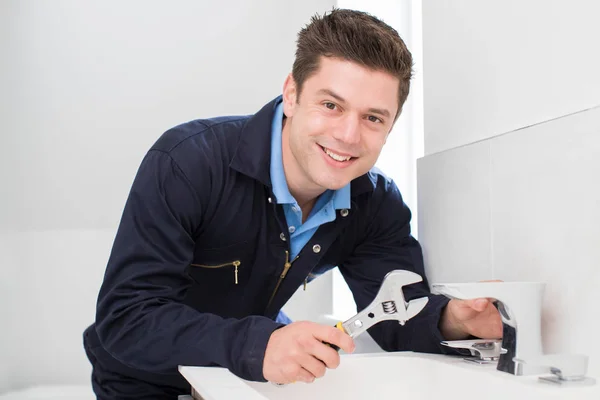 Retrato de fontanero trabajando en fregadero usando llave inglesa — Foto de Stock