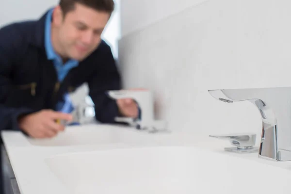 Tesisatçı anahtarı kullanarak banyoda Lavabonun üzerinde çalışıyor — Stok fotoğraf