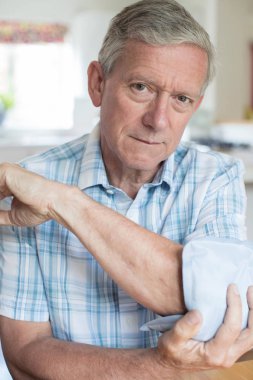 Portrait Of Mature Man Putting Ice Pack On Painful Elbow clipart