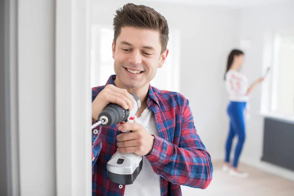 Homem usando broca elétrica como casal renovar propriedade juntos — Fotografia de Stock