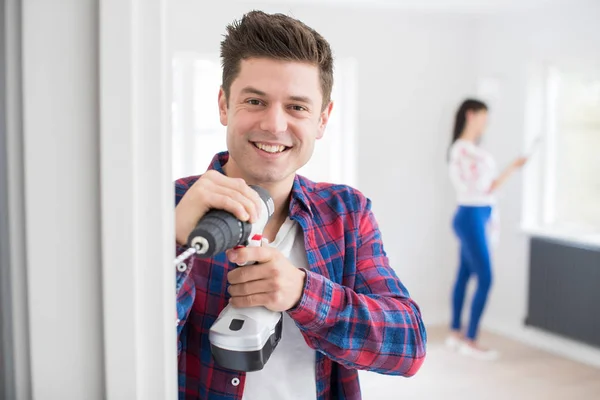 Homem usando broca elétrica como casal renovar propriedade juntos — Fotografia de Stock