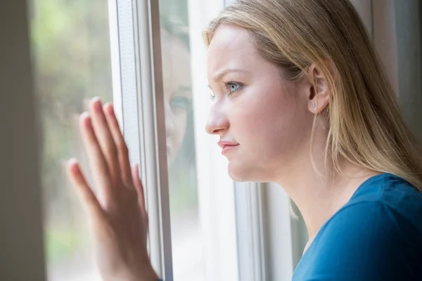 Triste giovane donna che soffre di depressione guardando fuori dalla finestra — Foto Stock