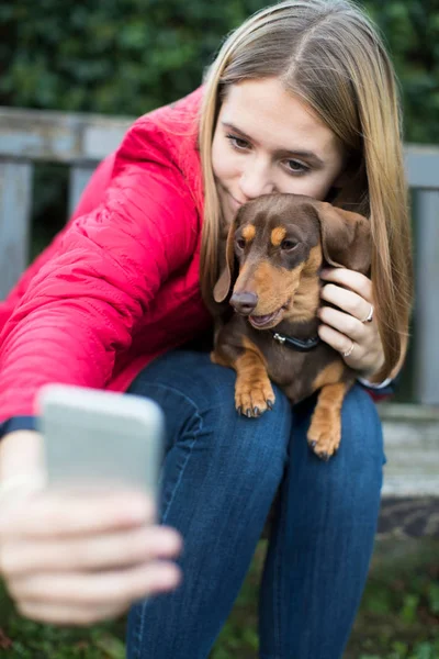 Adolescente chica con mascota dachshund posando para selfie — Foto de Stock