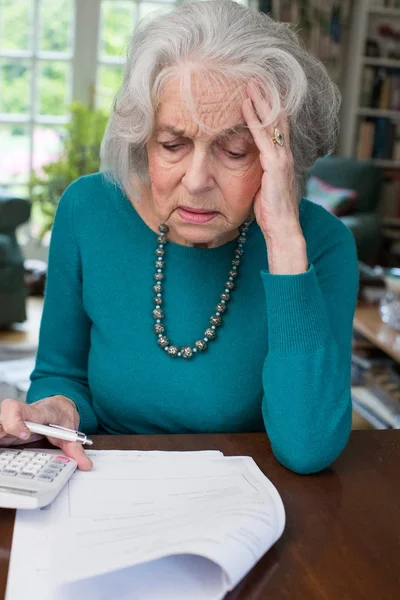 Seniorin geht Rechnungen durch und schaut besorgt — Stockfoto