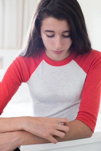 Ragazza adolescente seduta in camera da letto graffiare braccio — Foto Stock