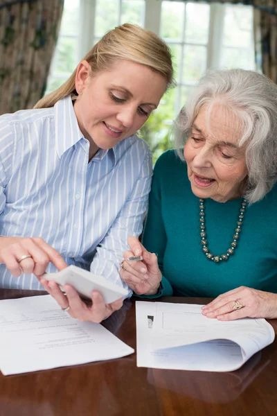 Vrouw helpen Senior buurman met papierwerk — Stockfoto